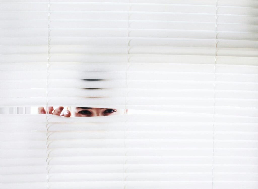 woman peeking through blinds